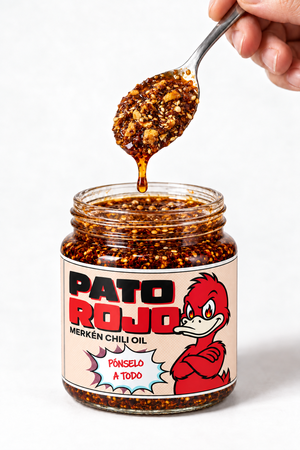 Una cucharada de chili oil sobre el frasco abierto de Pato Rojo con etiqueta oficial